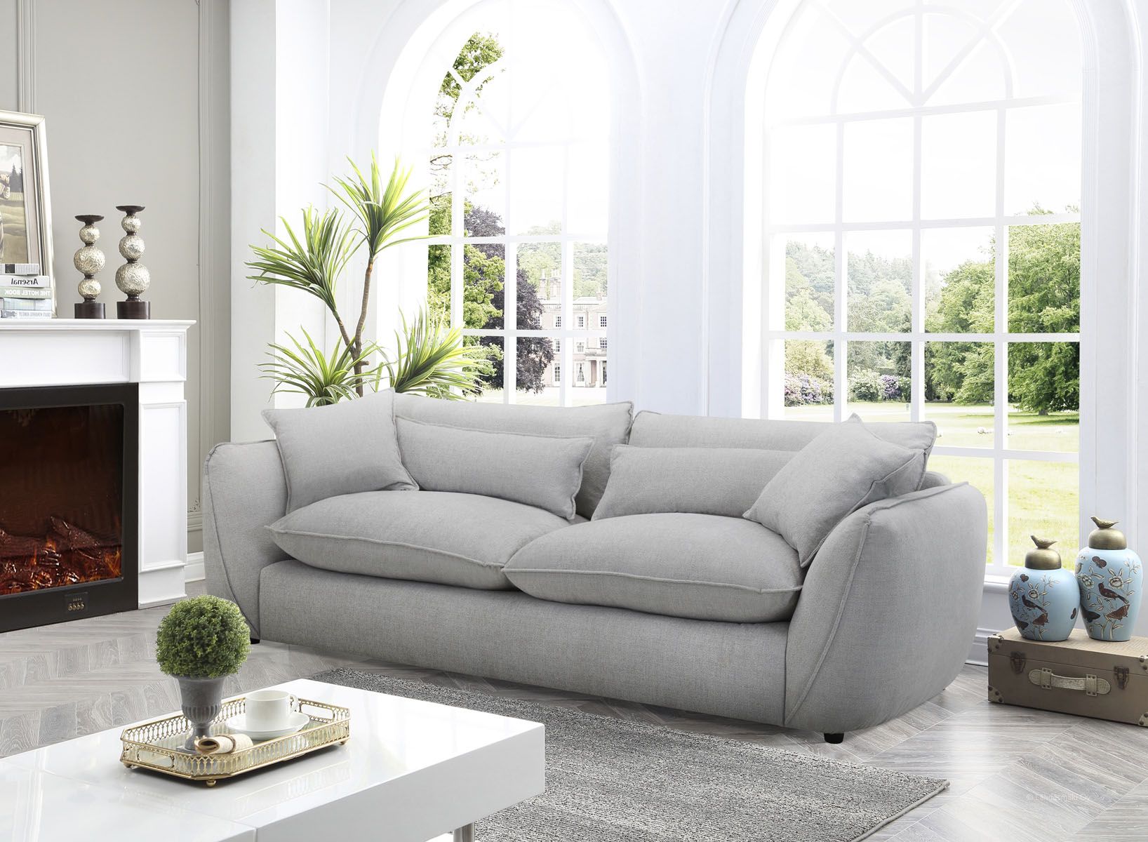 Muhkea 3,5-istuttava sohva harmaalla kangasverhoilulla. Muhkeat irtotyynyt sekä koristetyynyt.