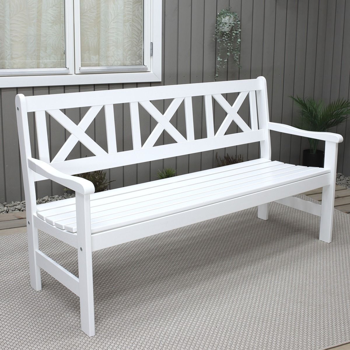 Valkoinen puutarhapenkki jossa on ristikkoselkä terassilla