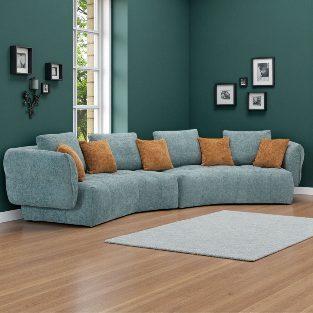 Kaareva turkoosi iso sohva, jossa on oranssit tyynyt