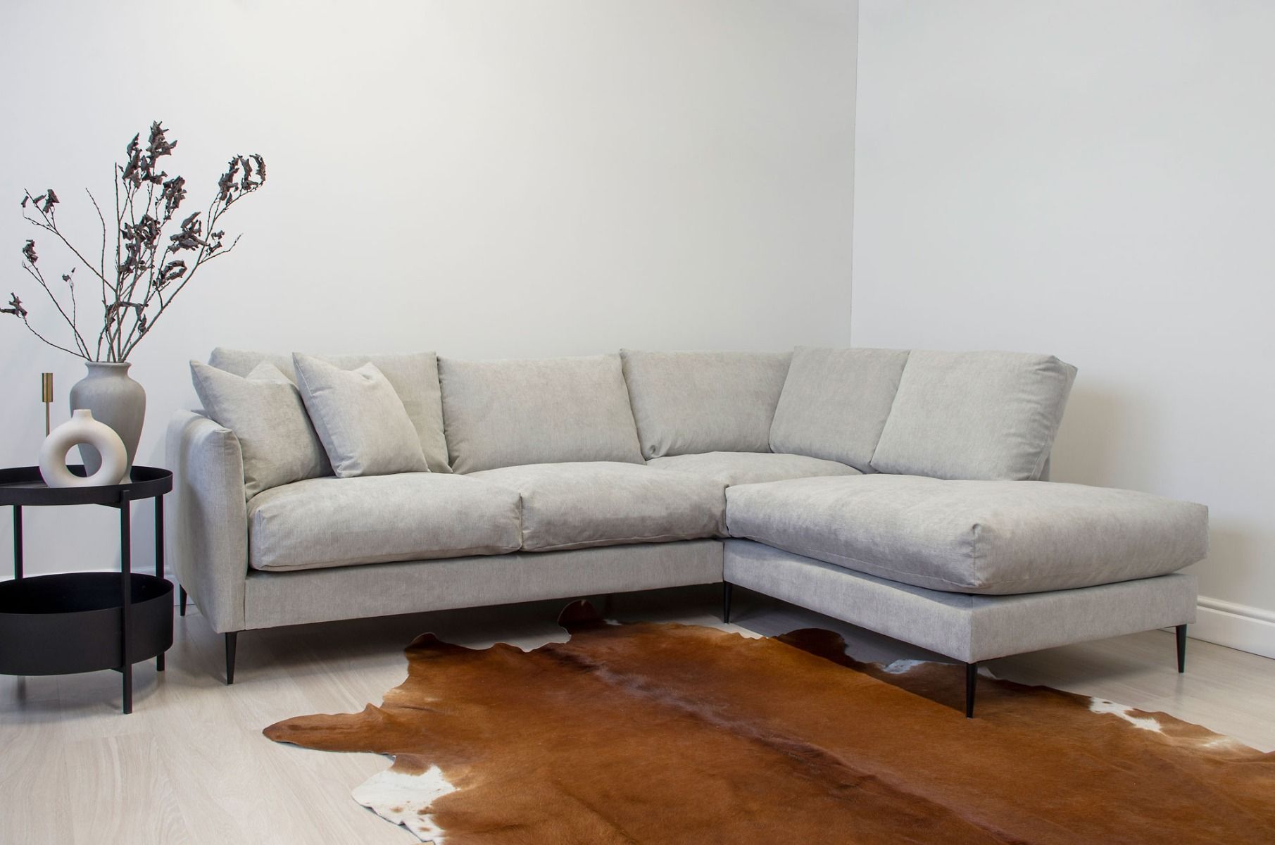 Vaaleanharmaa kulmasohva höyhentyynyillä