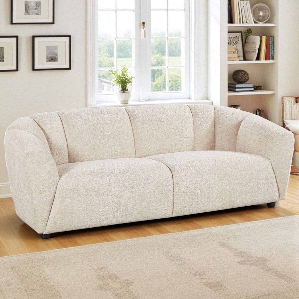 Nova sohva vaalealla kangasverhoilulla kuvattuna tyylikkässä sisustuksessa. Sohvassa on pyöreä muoto ja pörröinen kangas